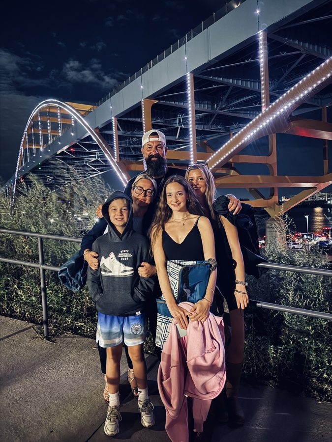 A group posing by a roller coaster at night