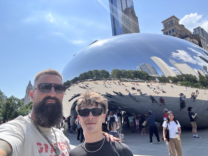 Two travelers taking a selfie beside Cloud Gate