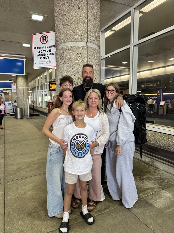 A group posing together outside an airport terminal