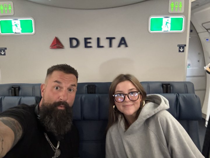 Two travelers taking a selfie aboard an airplane