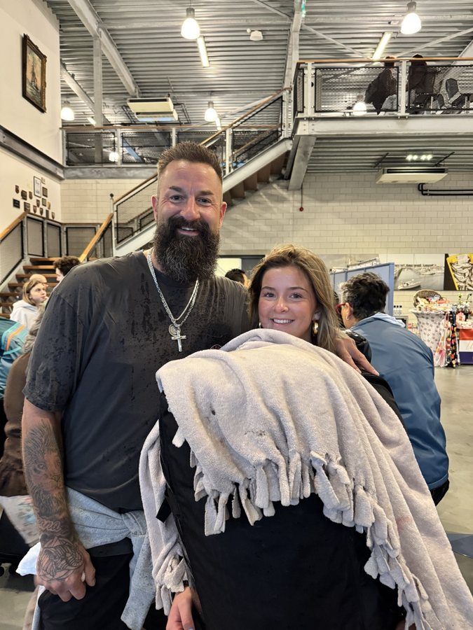 Two travelers posing together with a blanket in a terminal