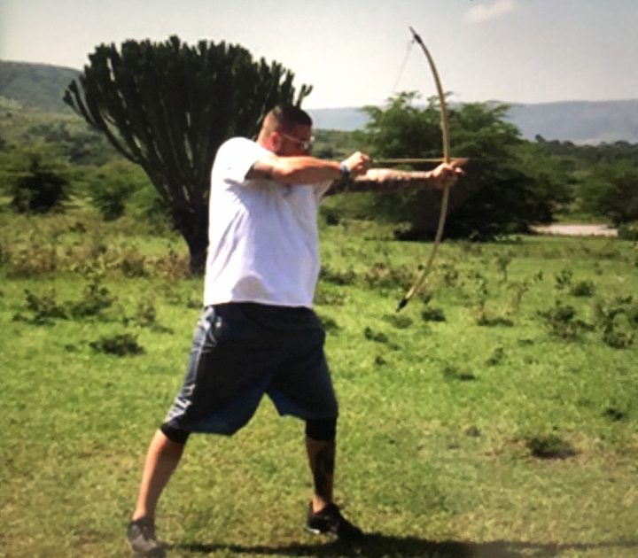 Practicing archery in an open grassy landscape