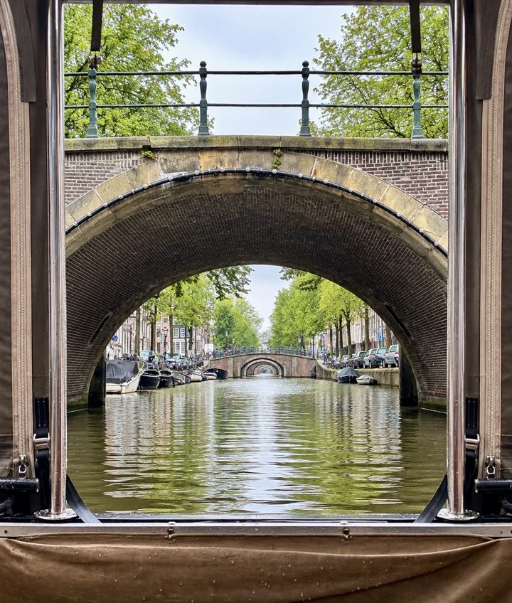 A view along a canal beneath a stone bridge